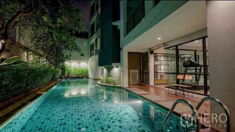 零售空间 出售在Phra Nakhon, Bangkok - 夜间长条马赛克泳池，旁有玻璃墙健身房与绿篱。