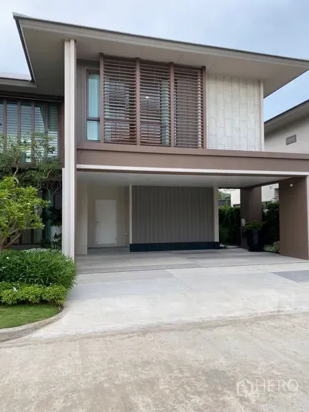 บ้าน ขายในBang Kapi, Bangkok - ที่จอดรถมีหลังคา 2–3 คัน ใต้ชั้นสองยื่น พร้อมระแนงไม้และพุ่มไม้