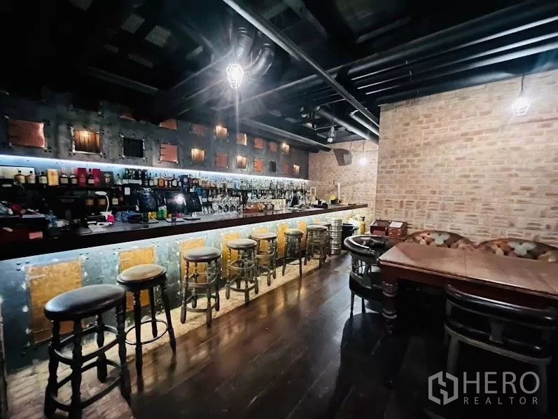 零售空间 出租在Watthana, Bangkok - 长吧台配高脚凳，外露砖墙、吊灯与木地板的两层场地。