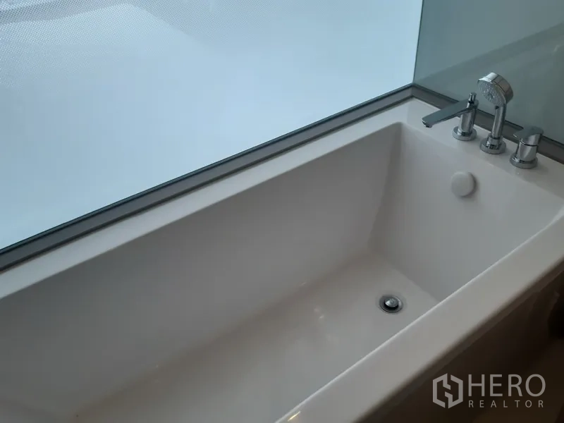 公寓 出租或出售在Watthana, Bangkok - 长方形浴缸临隐私窗，配镀铬龙头。