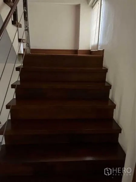 ทาวน์เฮาส์ ขายในPhra Khanong, Bangkok - บันไดไม้พร้อมราวสแตนเลสและหน้าต่างข้าง ทางขึ้นสู่ชั้นบน