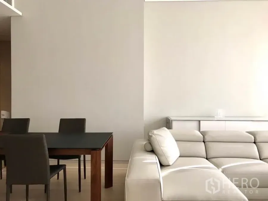 คอนโด ให้เช่าหรือขายในWatthana, Bangkok - ห้องนั่งเล่นและรับประทานอาหารโทนสว่าง โซฟาหนังสีอ่อน โต๊ะกินข้าวท็อปดำ สไตล์มินิมอล