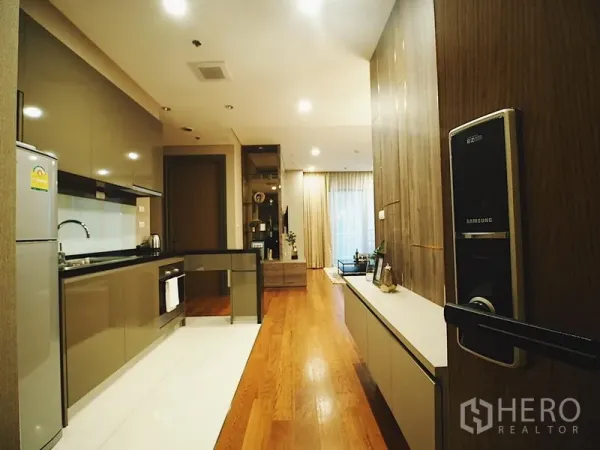 คอนโด ให้เช่าในKhlong Toei, Bangkok - มุมทางเข้าเห็นครัวแบบแกลลี่และพื้นที่นั่งเล่นพื้นไม้ พร้อมประตูดิจิทัล