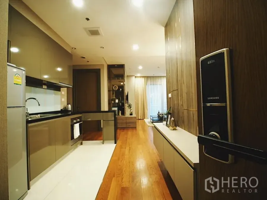 คอนโด ให้เช่าในKhlong Toei, Bangkok - มุมทางเข้าเห็นครัวแบบแกลลี่และพื้นที่นั่งเล่นพื้นไม้ พร้อมประตูดิจิทัล