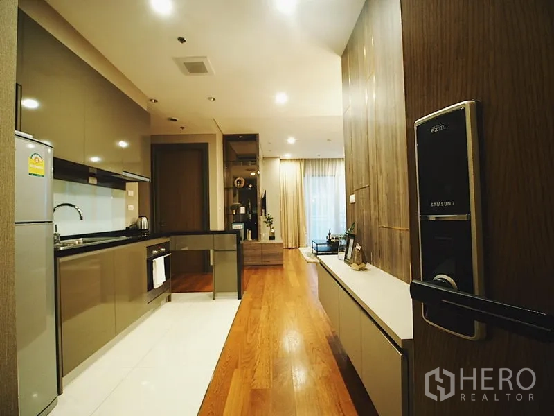 คอนโด ให้เช่าในKhlong Toei, Bangkok - มุมทางเข้าเห็นครัวแบบแกลลี่และพื้นที่นั่งเล่นพื้นไม้ พร้อมประตูดิจิทัล