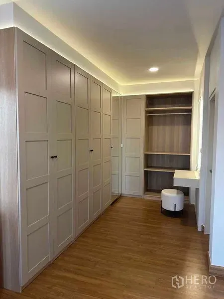 Detached House for rent in Bang Phli, Samut Prakan - Walk-in closet with built-in wardrobes, open shelving and a vanity with stool under warm lighting.