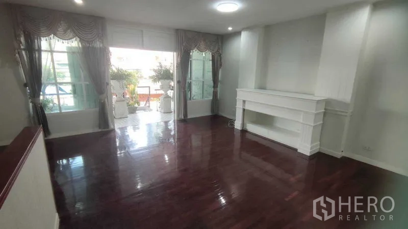 Home Office for rent in Watthana, Bangkok - Upper living room with glossy wooden floor and built-in shelving opening to terrace.