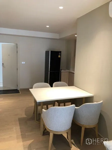 Condominium for rent in Watthana, Bangkok - Dining corner with table and four upholstered chairs beside the kitchen and entryway.