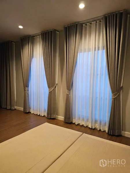 Detached House for rent in Mueang Pathum Thani, Pathum Thani - Bedroom corner with three tall windows dressed in layered curtains