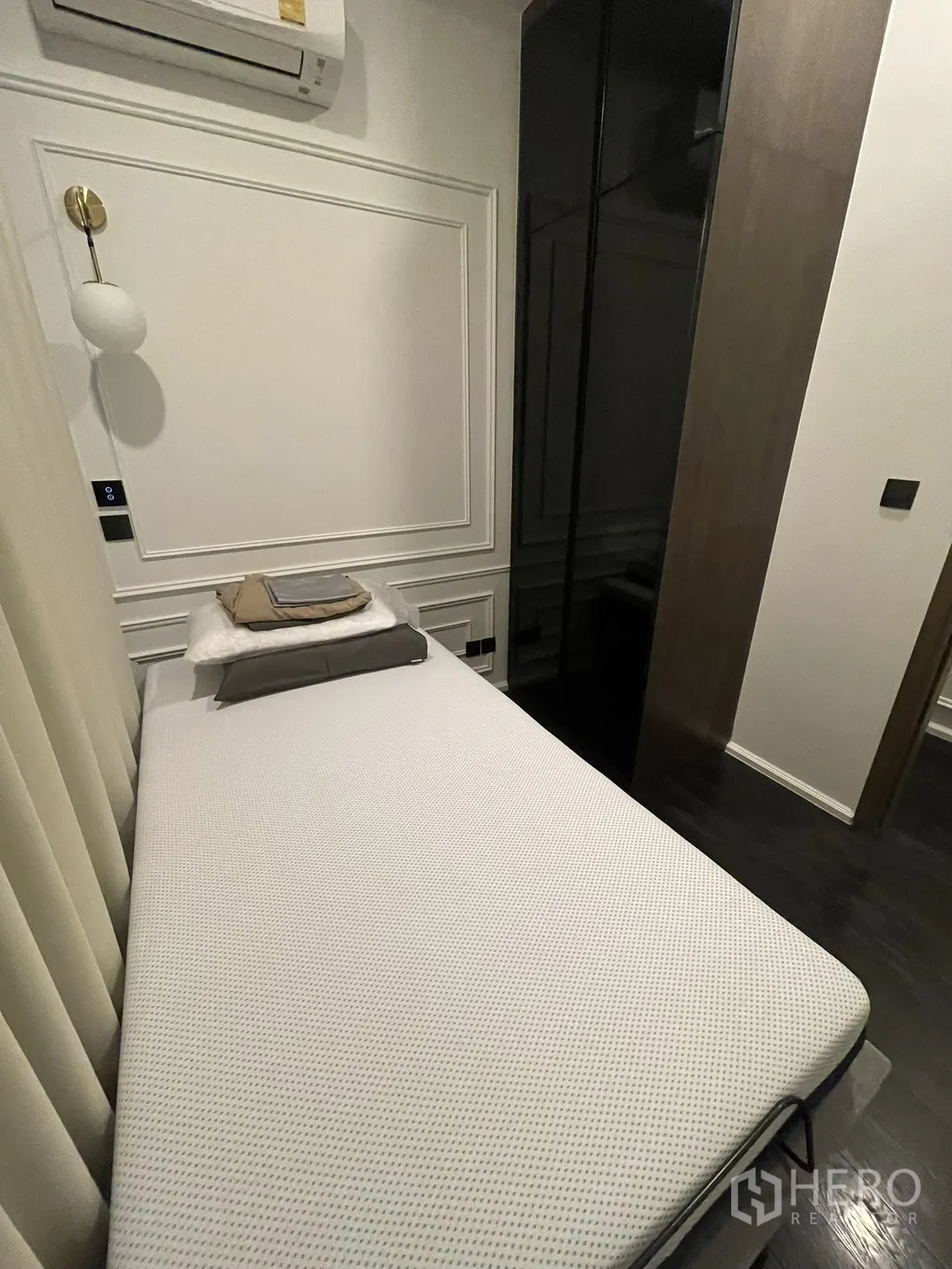 Condominium for rent in Watthana, Bangkok - Compact second bedroom with single bed, air conditioner, and wardrobe.