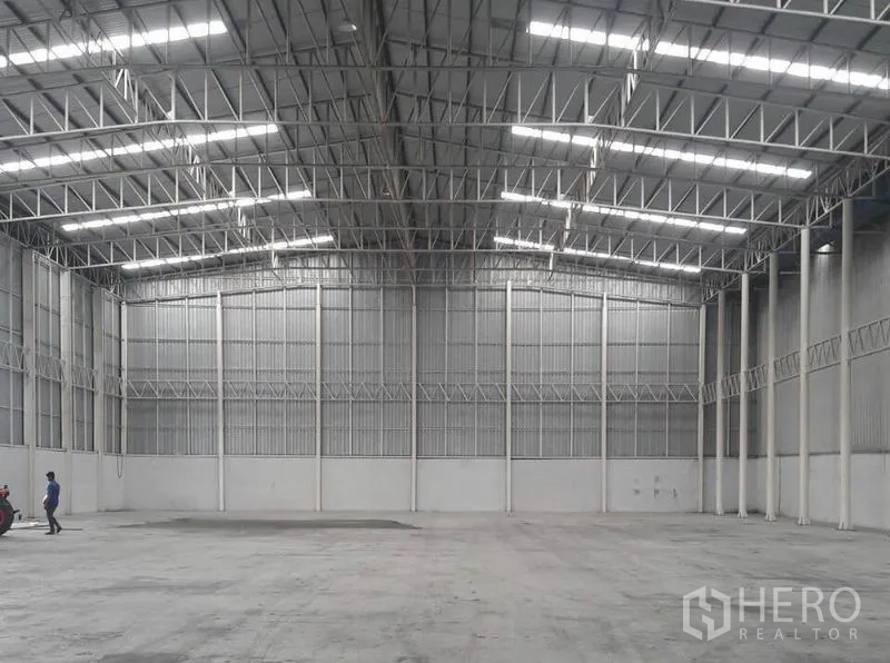 Warehouse for rent in Phra Nakhon Si Ayutthaya - Open industrial warehouse hall with illuminated steel roof and clear-span layout.