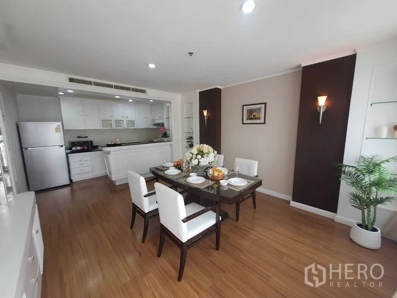 房间 出租在Watthana, Bangkok - 餐区摆放四人玻璃餐桌，邻接明亮白色厨房