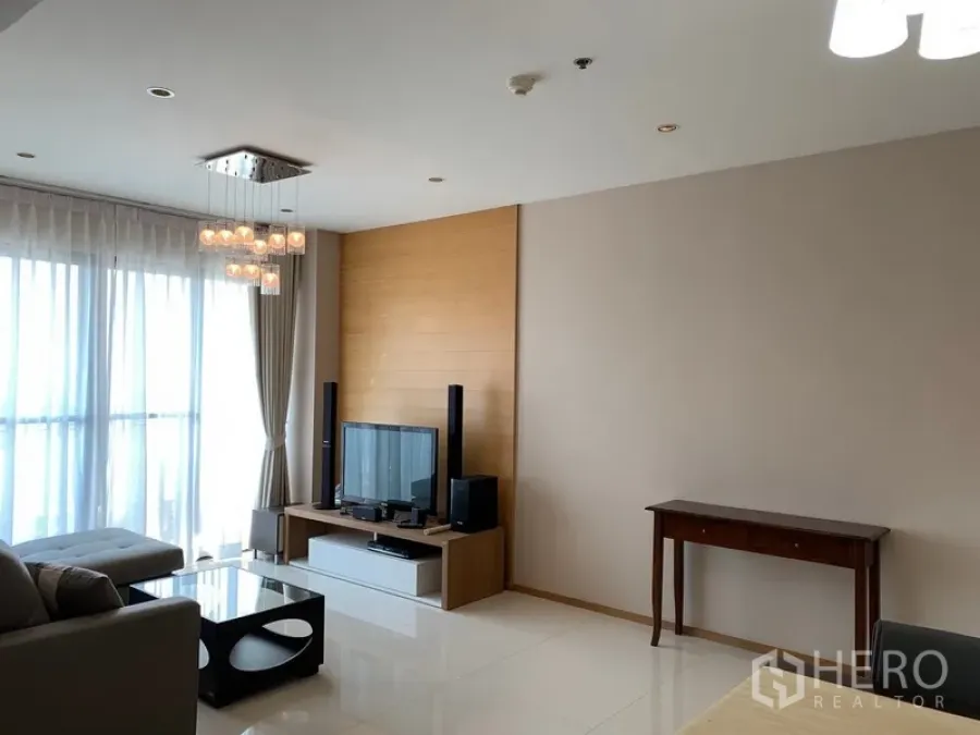 公寓 出租在Khlong Toei, Bangkok - 采光充足的客厅，落地窗、吊灯、沙发与电视柜。