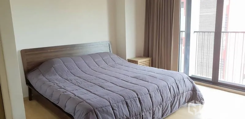 Condominium for rent in Watthana, Bangkok - Bright bedroom with a large bed, wood flooring, full-height glass doors and balcony access with curtains.