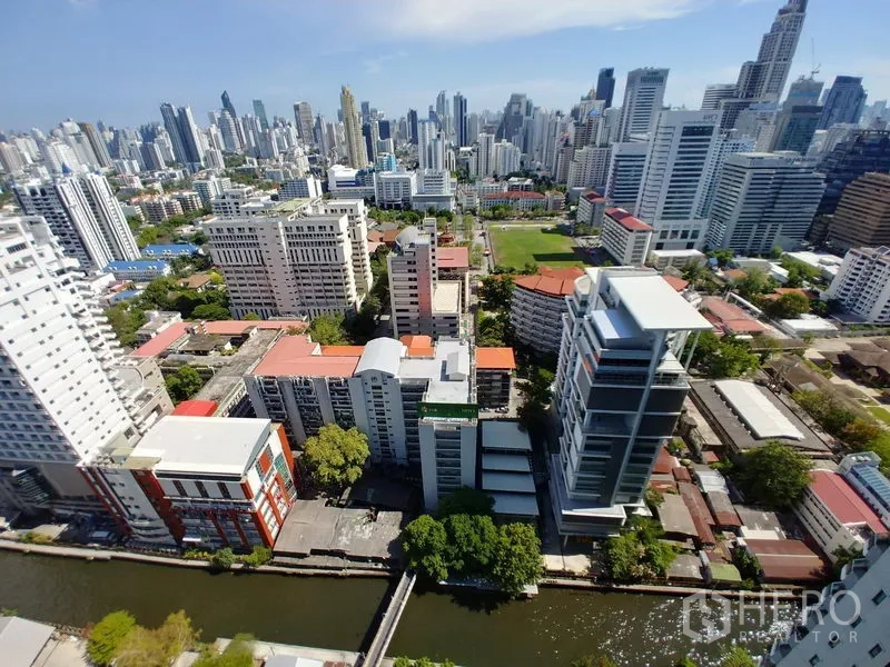 Condominium for rent in Huai Khwang, Bangkok - High-floor view of central Bangkok’s skyline overlooking a canal and city towers.