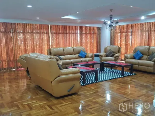 คอนโด ให้เช่าในWatthana, Bangkok - ห้องนั่งเล่นขนาดใหญ่ โซฟาหนังสีน้ำตาลอ่อน โคมแชนเดอเรีย และผ้าม่านสูงจรดเพดานบนพื้นปาร์เกต์