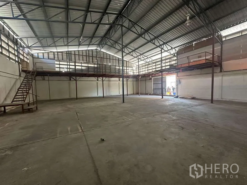 Warehouse for rent in Suan Luang, Bangkok - Spacious warehouse interior with high steel-truss roof, mezzanine platforms and a large loading door.