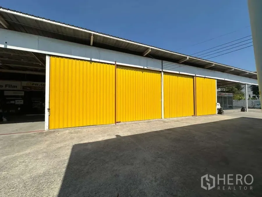 货栈 出租在Bang Khen, Bangkok - 邦肯仓库的黄色钢制推拉门与宽阔混凝土装卸 yard。