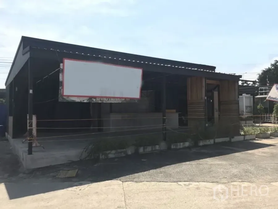 零售空间 出租在Khlong Toei, Bangkok - 单层零售铺位，钢结构屋顶，前方空白招牌框与前院停车空间，临近Phra Khanong。