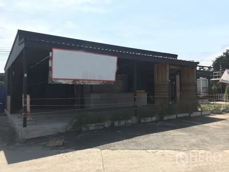 零售空间 出租在Khlong Toei, Bangkok - 单层零售铺位，钢结构屋顶，前方空白招牌框与前院停车空间，临近Phra Khanong。