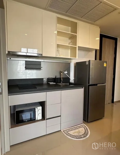 คอนโด ให้เช่า - ครัวรูปแบบเส้นตรงขนาดกระทัดรัด เตาอินดักชัน ไมโครเวฟ และตู้เย็นสแตนเลส