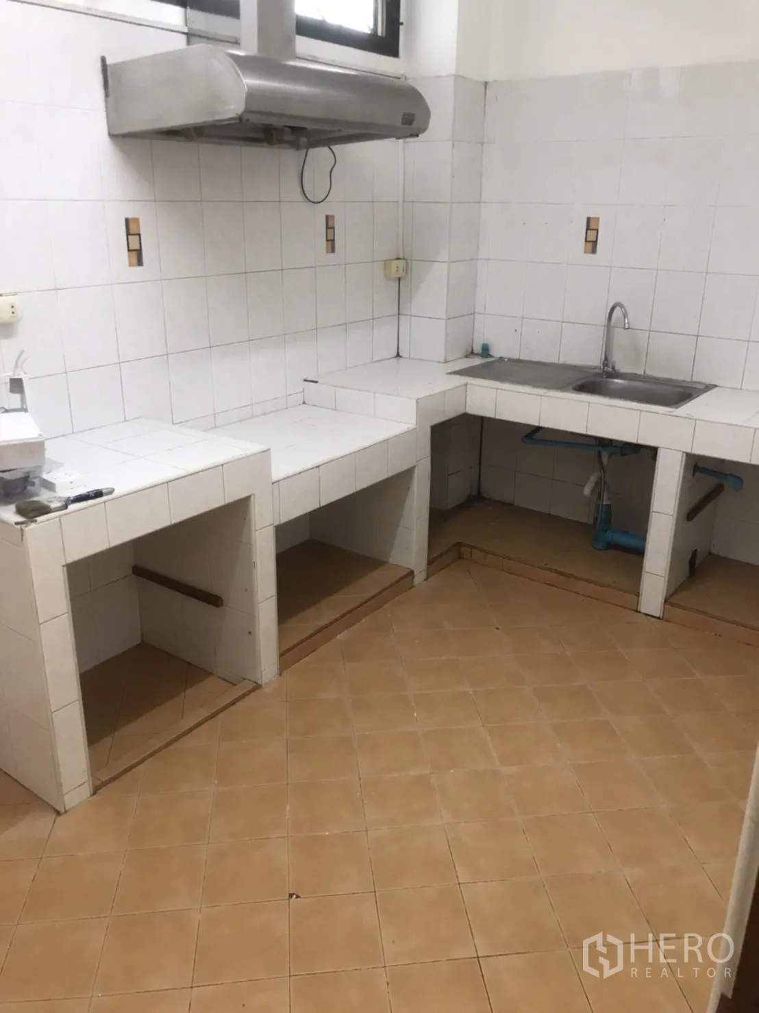 Home Office for rent in Khlong Toei, Bangkok - Thai-style kitchen with tiled counters, stainless range hood, and sink.
