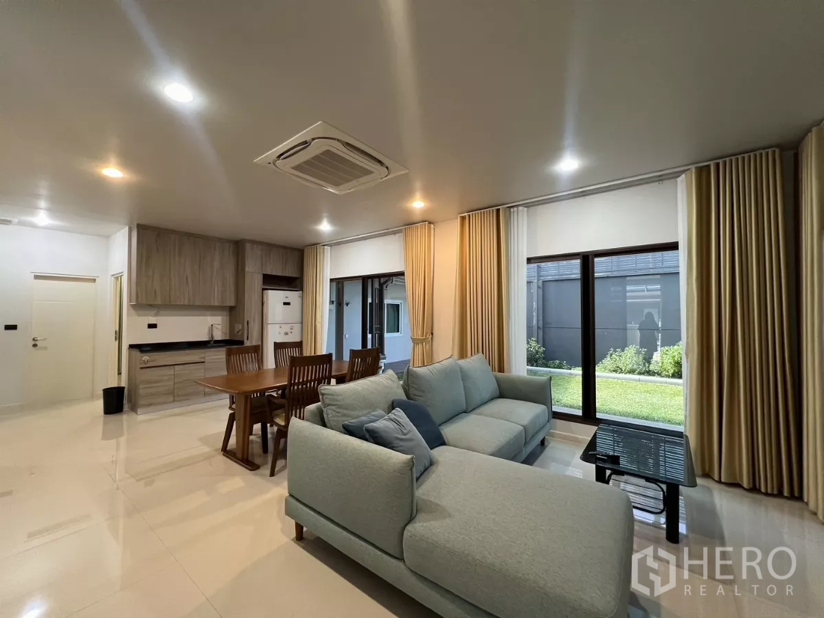 Detached House for rent or sale in Bang Kapi, Bangkok - Living area facing the garden with sliding doors and beige curtains