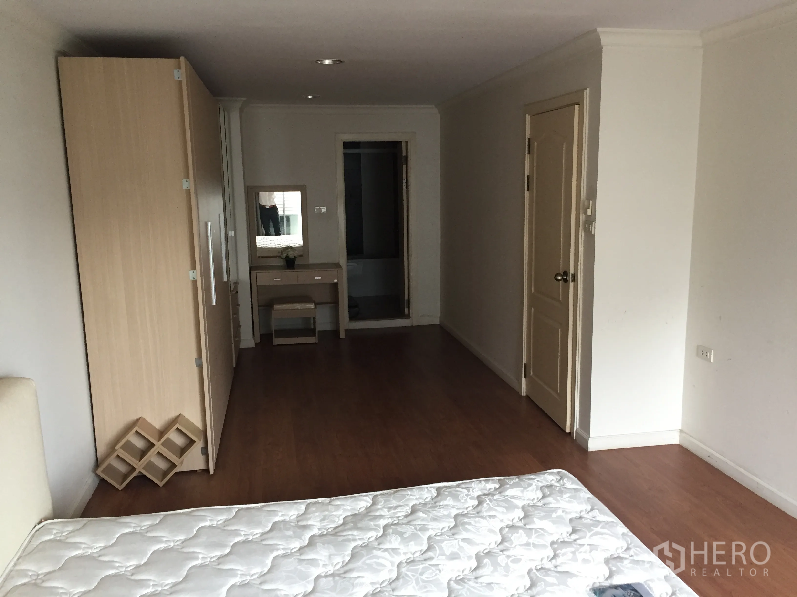 คอนโด ให้เช่าในWatthana, Bangkok - ห้องนอนกว้าง พื้นไม้ ตู้เสื้อผ้าสีอ่อน โต๊ะเครื่องแป้ง และประตูเข้าห้องน้ำ