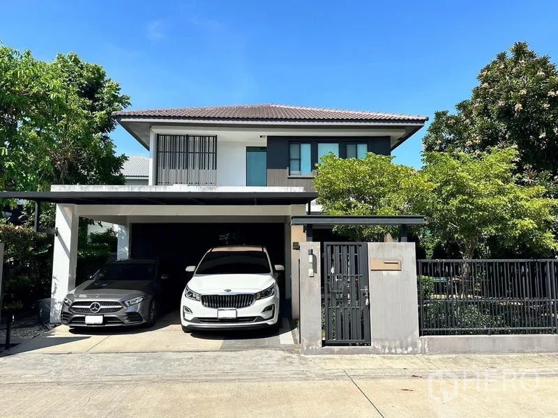 Detached House for rent in Bang Phli, Samut Prakan - Modern two-storey detached house in Bang Phli with gated fence, mature trees and a covered two-car carport.