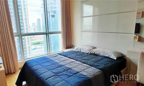 คอนโด ให้เช่าในRatchathewi, Bangkok - ห้องนอนพร้อมหน้าต่างบานใหญ่ เห็นสกายไลน์กรุงเทพฯ ผ้าคลุมเตียงสีน้ำเงิน