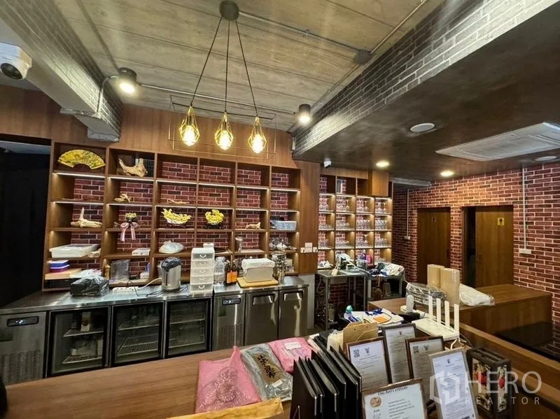店屋 出租在Watthana, Bangkok - 前台与展示货架，吊灯下的餐厅式布局