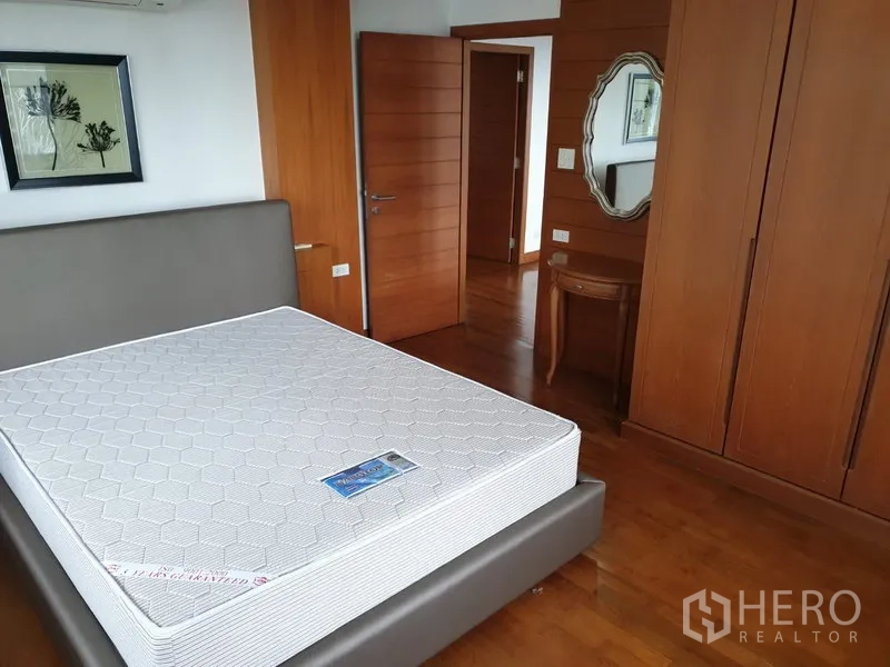 Condominium for rent in Watthana, Bangkok - Secondary bedroom with large wardrobe, wooden floors and wall mirror.