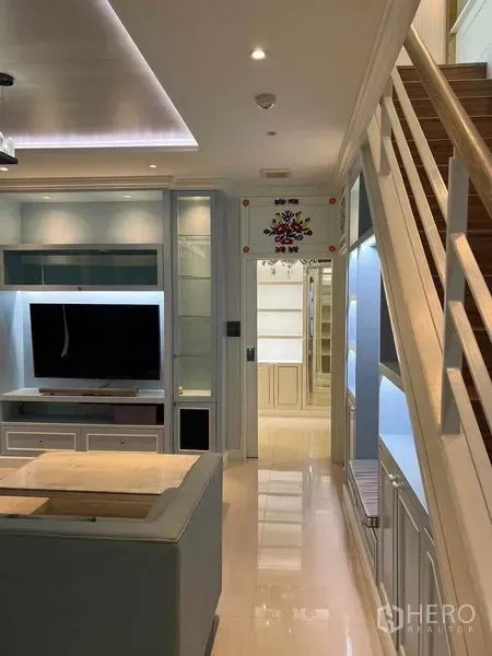 公寓 出售在Bang Na, Bangkok - 明亮客厅，定制电视柜与通往上层的楼梯。