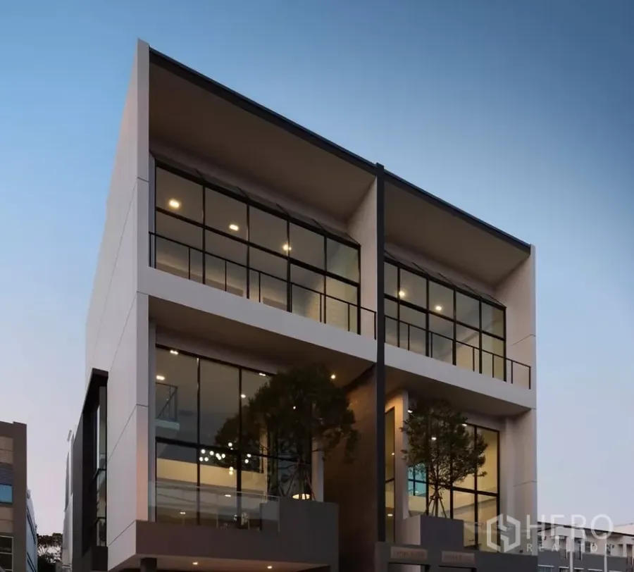 Home Office for sale in Bang Kapi, Bangkok - Modern multi-storey home office facade with large glass windows at dusk in Bang Kapi.