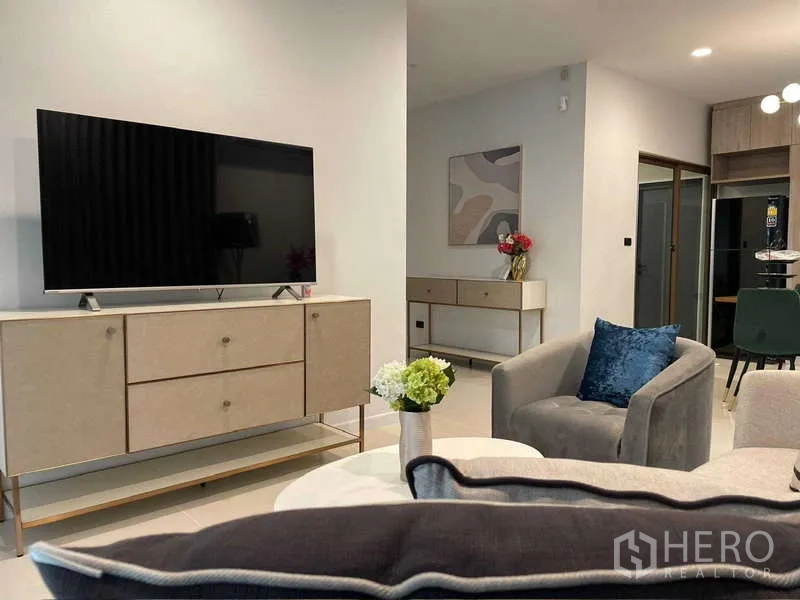 Detached House for rent in Bang Kapi, Bangkok - Living room with TV console, armchair and sofa in neutral tones.