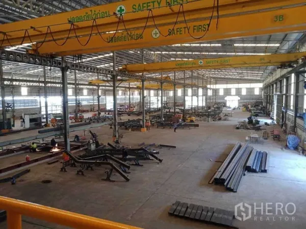 工厂 出售在Chachoengsao - 高跨车间配黄色桥机、天窗采光和成堆钢材。