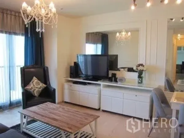 คอนโด ให้เช่าในKhlong Toei, Bangkok - ห้องนั่งเล่นสว่าง โคมระย้า ชั้นวางทีวี และประตูกระจกบานเลื่อนออกสู่ระเบียง