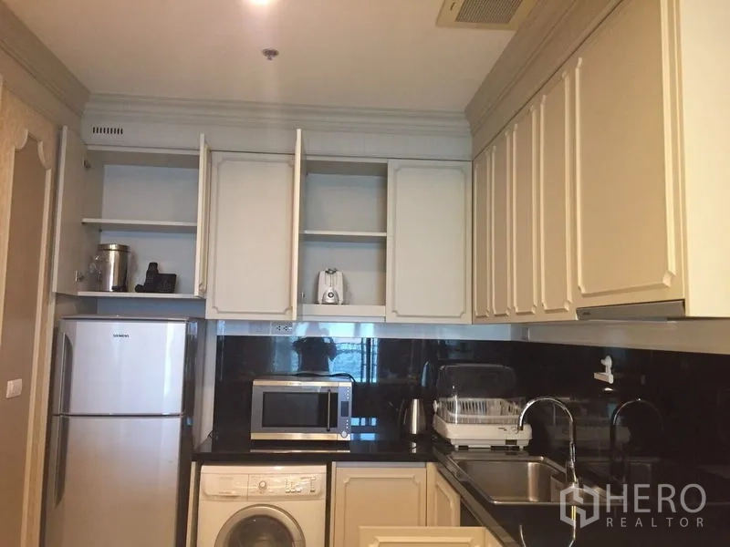 คอนโด ให้เช่าในKhlong Toei, Bangkok - ครัวบิลท์อินตู้สีขาว แผงกันเปื้อนสีดำ พร้อมตู้เย็น ไมโครเวฟ และเครื่องซักผ้า