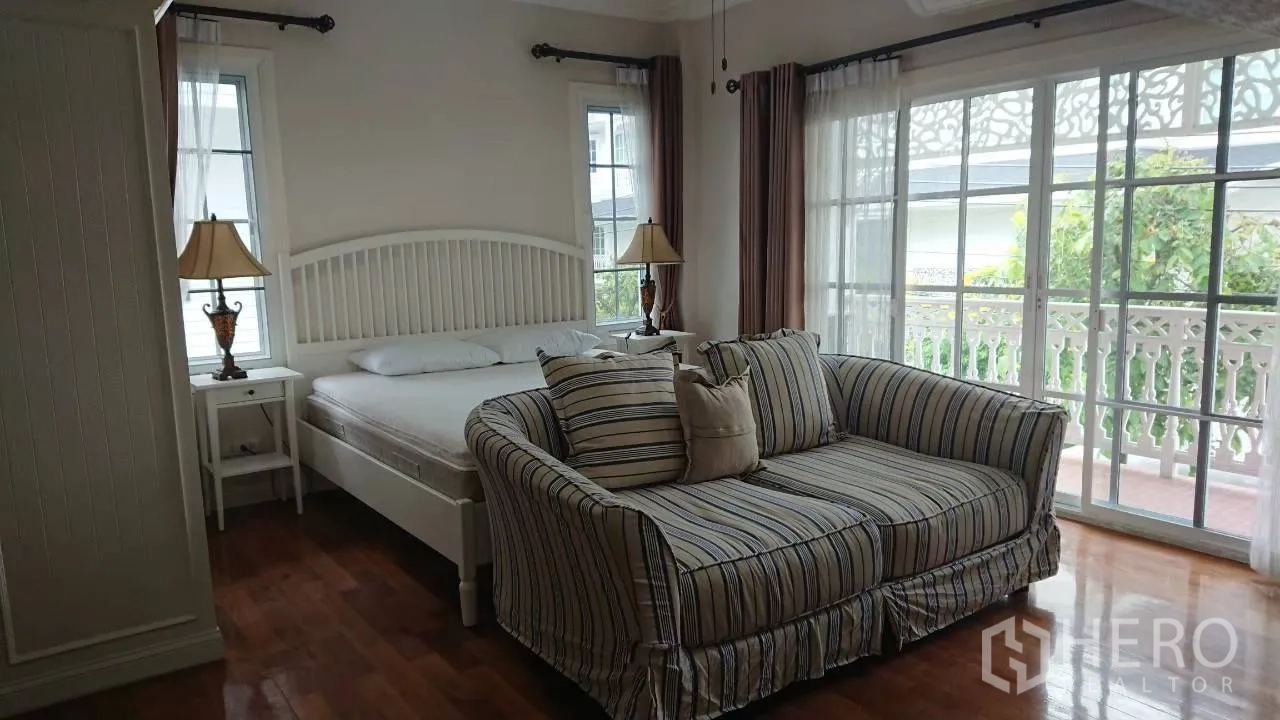 บ้าน ให้เช่าในMueang Samut Prakan, Samut Prakan - ห้องนอนใหญ่ เปิดสู่ระเบียง มีโซฟาลายทาง และหน้าต่างบานเลื่อนเต็มผนัง