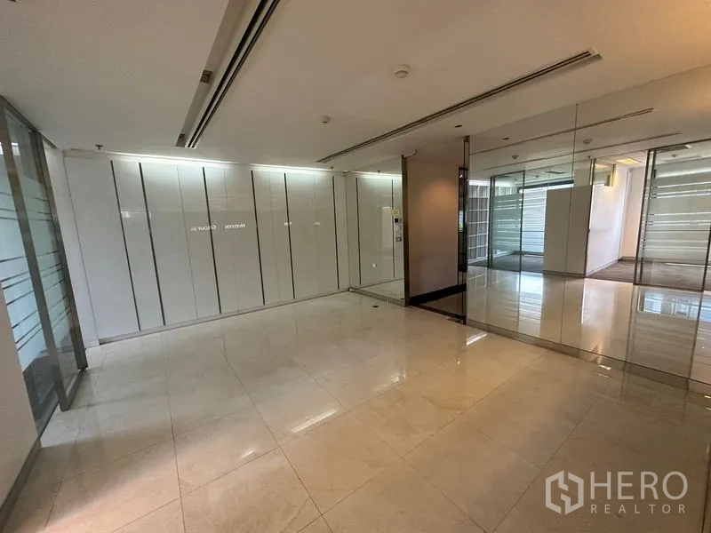 Office Space for rent - Lobby space with mirrored wall, light tile flooring and sliding glass doors.