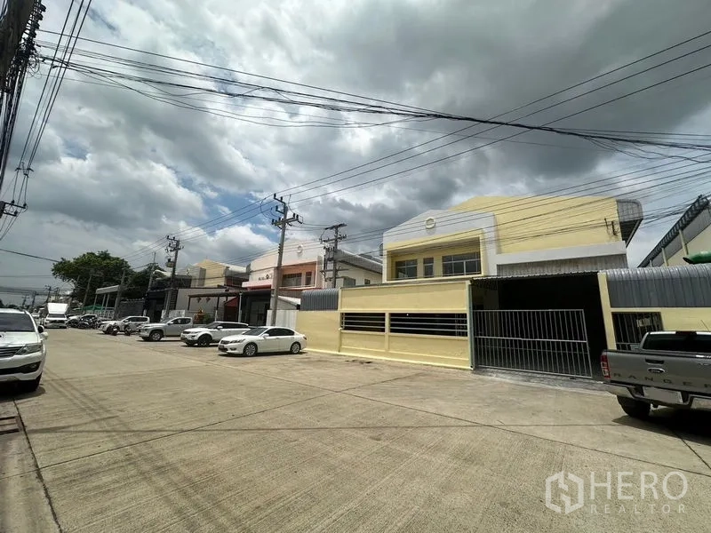 工厂 出租在Pathum Thani - 巴吞他尼空銮区宽阔混凝土路上的成排工厂建筑与铁门立面。
