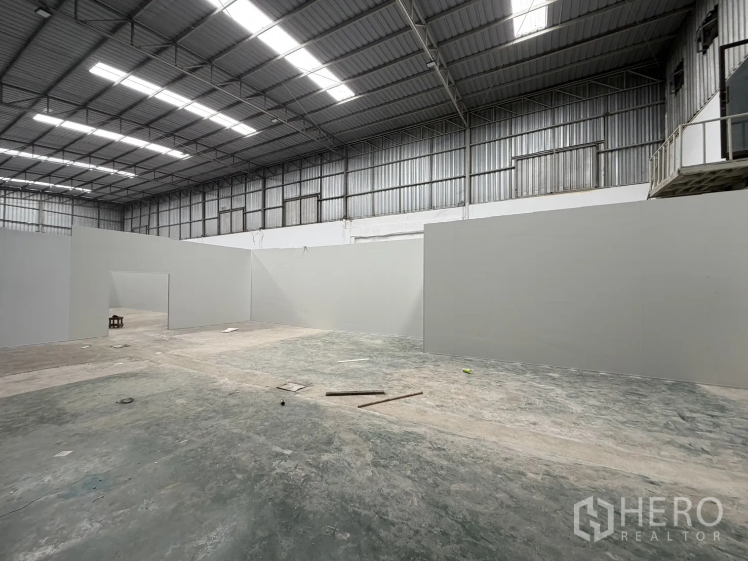 Warehouse for rent in Khlong Luang, Pathum Thani - Open floor beside partitioned rooms with a doorway and durable concrete surface.