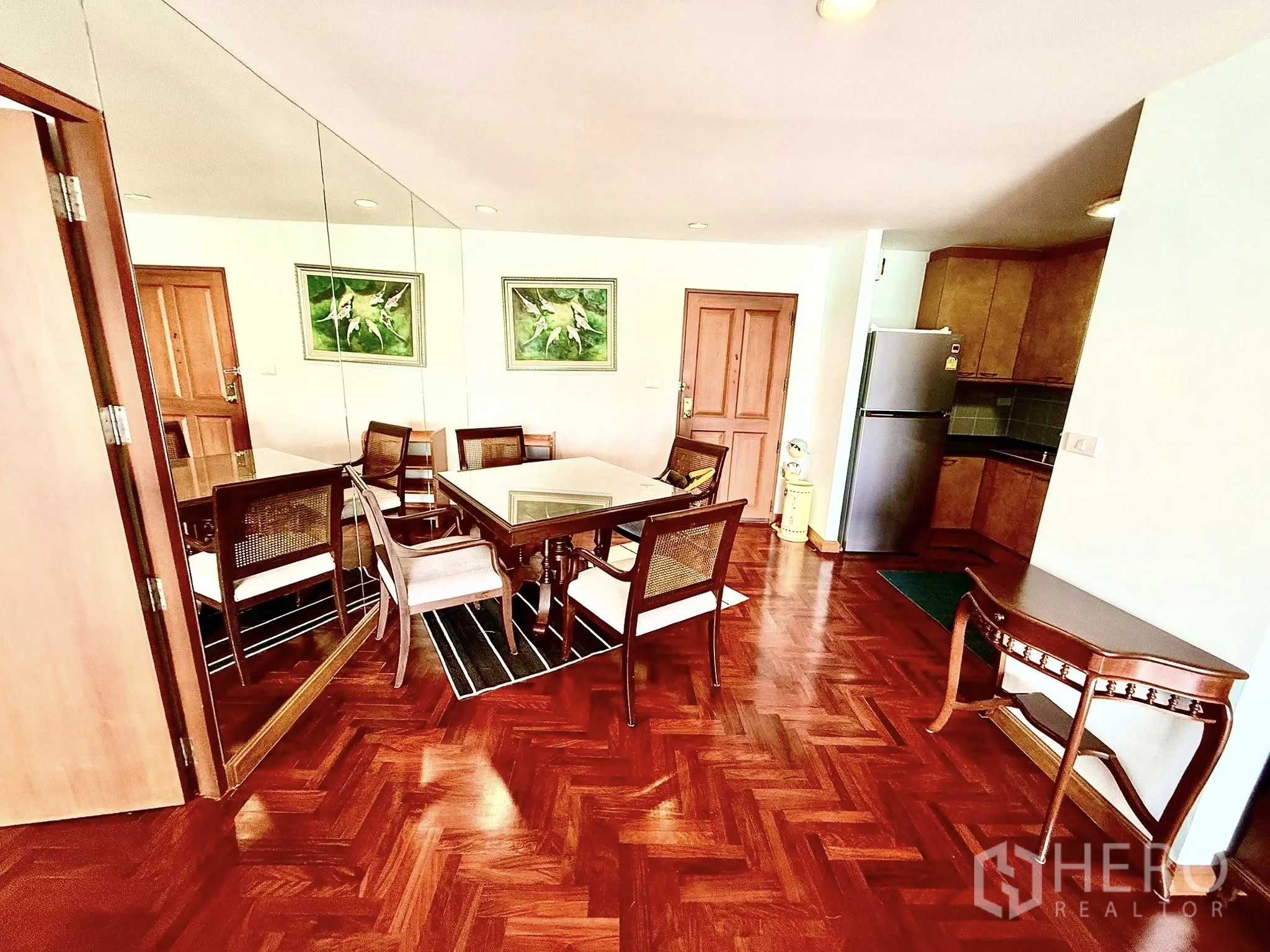 Condominium for rent in Sathon, Bangkok - Four‑seat dining table beside a mirror wall and entrance, adjacent to the kitchen.