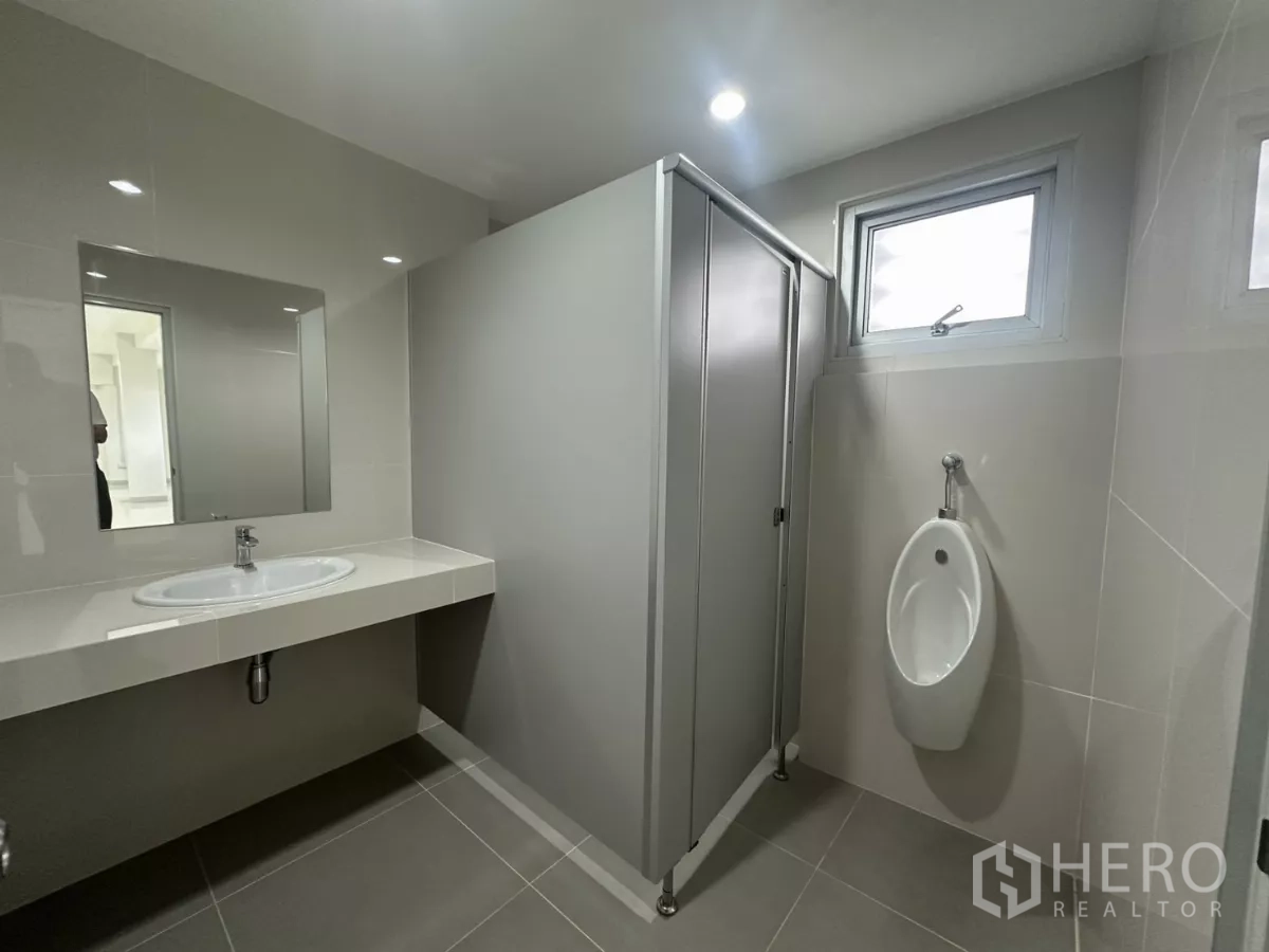 Factory for rent in Bang Phli, Samut Prakan - Upstairs restroom with urinal, stall and sink beneath windows.
