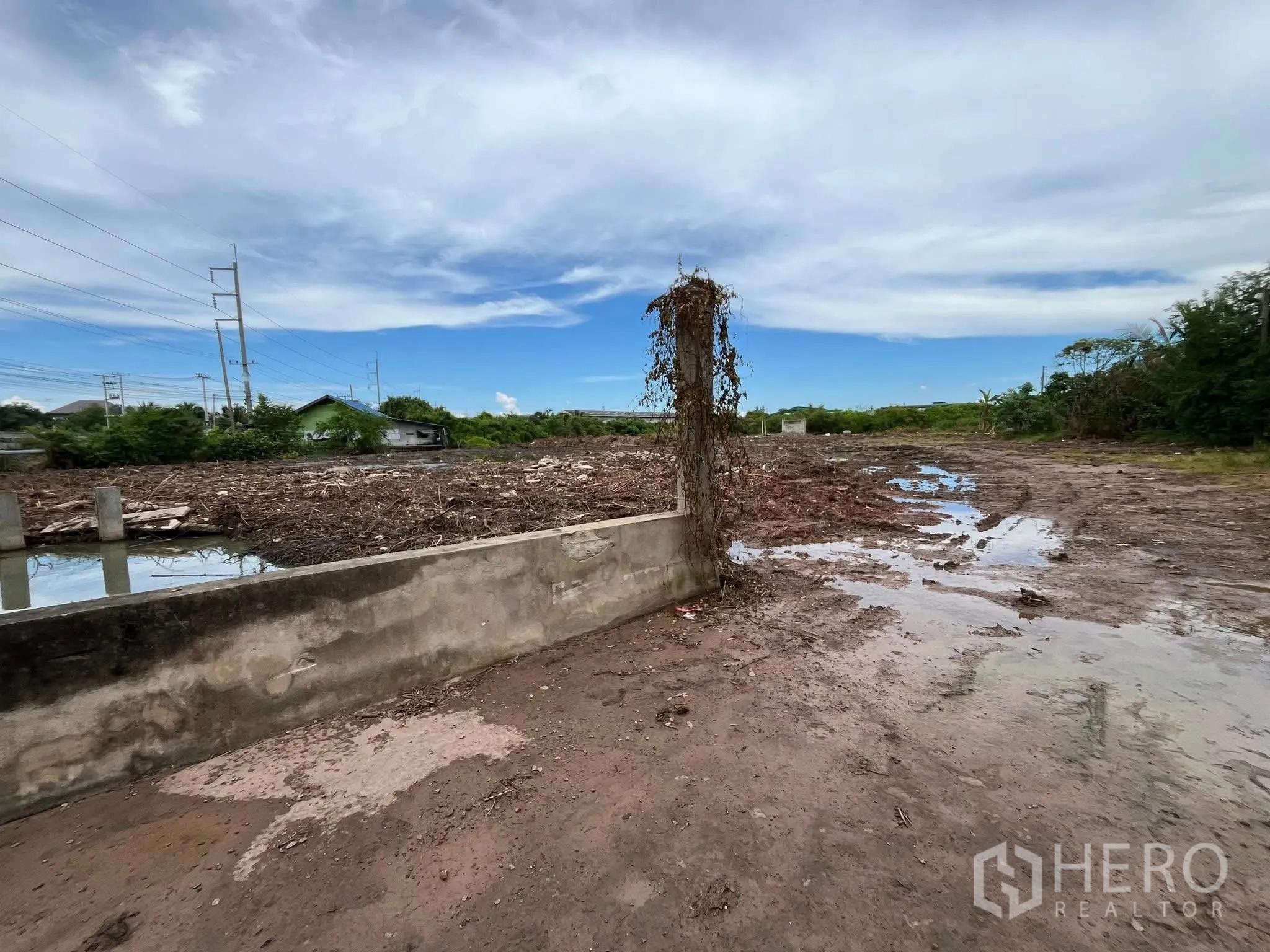 Land for sale in Mueang Samut Sakhon, Samut Sakhon - Cleared land with muddy ground, concrete boundary posts, and an adjacent drainage canal.