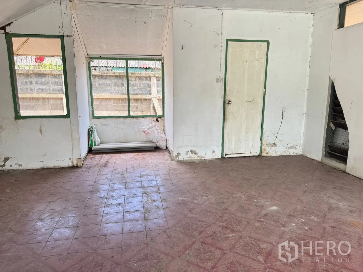 Detached House for rent in Mueang Samut Prakan, Samut Prakan - Empty interior room with tiled floor, white walls, windows and a simple door ready for renovation.
