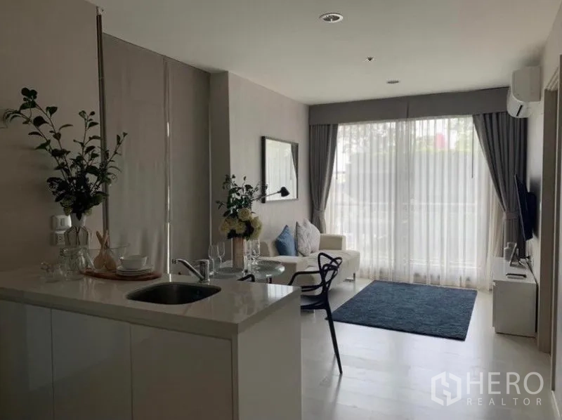 คอนโด ให้เช่าในKhlong Toei, Bangkok - ห้องนั่งเล่นแบบโอเพนแปลนพร้อมเคาน์เตอร์ครัวสีขาว โซฟา และผ้าม่านโปร่งแบบเต็มผนัง