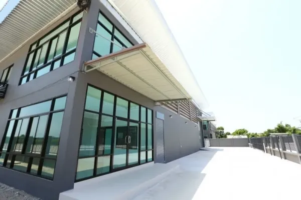 Factory for rent or sale in Bang Bo, Samut Prakan - Glass façade along the factory side with a covered loading area and wide walkway.