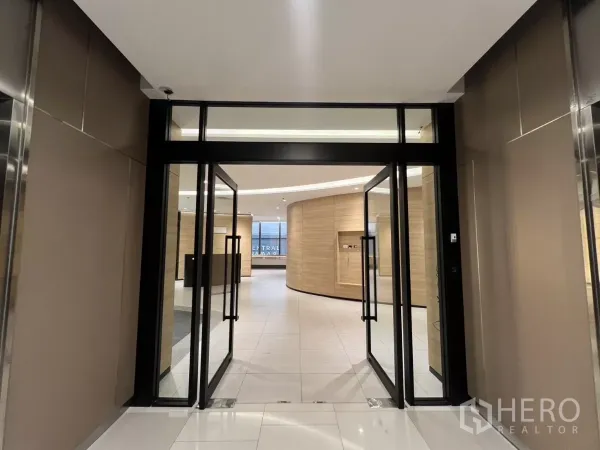 สำนักงาน ให้เช่าในHuai Khwang, Bangkok - ประตูกระจกบานคู่เปิดสู่ล็อบบี้สำนักงานสมัยใหม่ ผนังลายไม้ พื้นกระเบื้องสีขาว