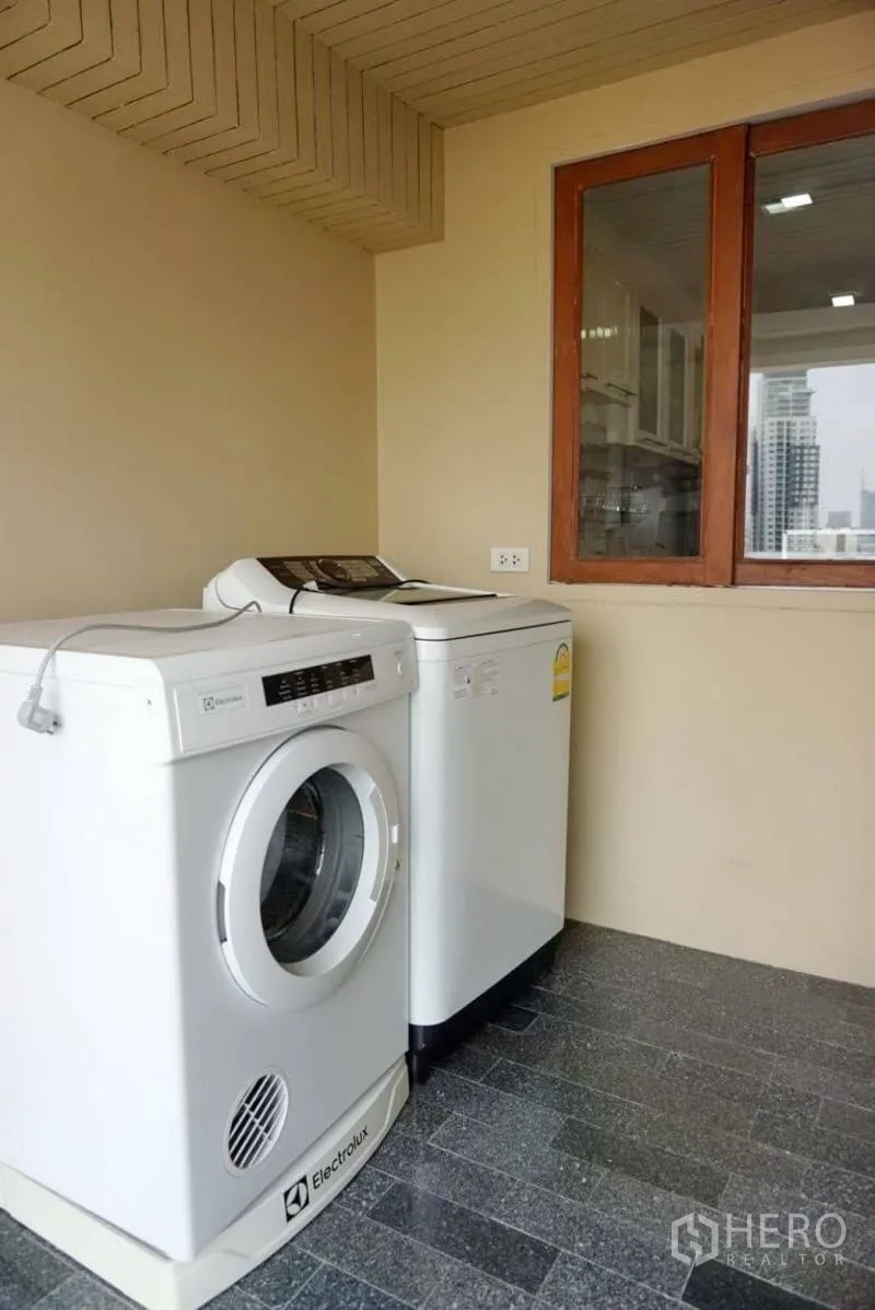 Condominium for rent in Watthana, Bangkok - Laundry area with front-load washer and top-load dryer overlooking the city.